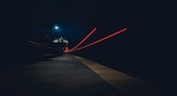 A night-time shot displaying two mysterious red light trails and a dim streetlight. Original public domain image from Wikimedia Commons