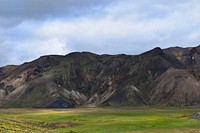 Jagged mountains tower over a green plain in Landmannalaugar. Original public domain image from Wikimedia Commons