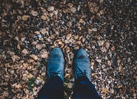 Looking down at a pair of blue boots in a pile of leaves on the floor in the autumn.. Original public domain image from Wikimedia Commons