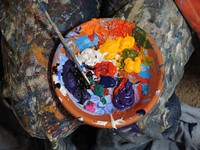 Mix of paints in a orange bowl with paintbrush sit on a messy background. Original public domain image from Wikimedia Commons