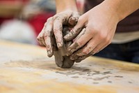 A clay stained hand of a potter engaging in a craft work of pottery or molding. Original public domain image from Wikimedia Commons