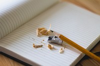 Pencil shavings around a pencil and a pencil sharpener on an open notebook. Original public domain image from Wikimedia Commons