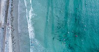 Drone aerial view of people in the ocean by the shore in Vazon. Original public domain image from <a href="https://commons.wikimedia.org/wiki/File:Surfing_in_Vazon_Bay,_Guernsey_(Unsplash).jpg" target="_blank" rel="noopener noreferrer nofollow">Wikimedia Commons</a>