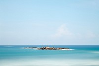 Single rock waterscape on horizon with clear blue sea and sky, Unawatuna Beach. Original public domain image from Wikimedia Commons