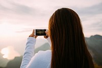 A woman taking a photo of the ocean view. Original public domain image from Wikimedia Commons