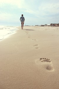 Woman wearing blue dress shirt and white short shorts walking on seashore. Original public domain image from Wikimedia Commons