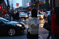 Young woman with white backpack standing on busy urban crossroads near traffic in San Francisco. Original public domain image from Wikimedia Commons