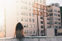 Woman in gray top sitting on a building's edge. Original public domain image from Wikimedia Commons