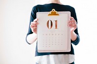 A woman holding up a clipboard with a calendar in front of her chest. Original public domain image from Wikimedia Commons