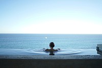 A woman bathing in a pool overlooking a vast blue ocean. Original public domain image from Wikimedia Commons