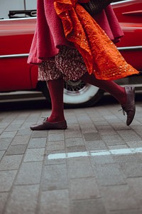 Woman dressed in red walking in front of vintage red car at Lewis Cubitt Square. Original public domain image from Wikimedia Commons