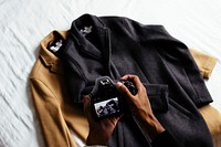 A person taking a photo of two coats with a camera. Original public domain image from <a href="https://commons.wikimedia.org/wiki/File:Photographing_coats_(Unsplash).jpg" target="_blank" rel="noopener noreferrer nofollow">Wikimedia Commons</a>