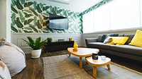 A room with palm print wallpaper, bean bag chairs, a couch, coffee table, rug, and tv at Communal Coworking. Original public domain image from Wikimedia Commons