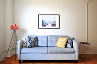 Gray couch with decorative pillows and unique art in a cozy apartment living room. Original public domain image from Wikimedia Commons