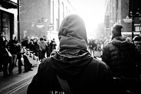 A black and white shot from behind civilians wearing hooded jackets and walking through London. Original public domain image from <a href="https://commons.wikimedia.org/wiki/File:Assassin%27s_creed_(Unsplash).jpg" target="_blank" rel="noopener noreferrer nofollow">Wikimedia Commons</a>