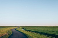 A winding road through a green meadow. Original public domain image from Wikimedia Commons