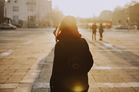 A woman in a scarf in a Budapest city square faces away toward the sunset. Original public domain image from Wikimedia Commons