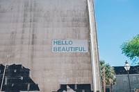 Green hello beautiful sign on urban wall with blue sky in background, Charleston. Original public domain image from Wikimedia Commons