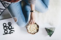 A person in ripped jeans eating popcorn alongside a succulent plant and typographic sample. Original public domain image from Wikimedia Commons