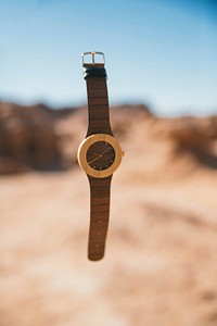 An elegant watch floating in the air above a desert. Original public domain image from Wikimedia Commons
