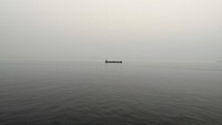 Boat alone on calm gray waters on an overcast foggy morning. Original public domain image from Wikimedia Commons