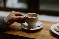 A person lifting up a cup of coffee from a saucer. Original public domain image from <a href="https://commons.wikimedia.org/wiki/File:Small_coffee_on_a_saucer_(Unsplash).jpg" target="_blank" rel="noopener noreferrer nofollow">Wikimedia Commons</a>