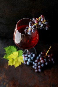 Macro view of a wine glass containing alcoholic wine with a bunch of grapes. Original public domain image from <a href="https://commons.wikimedia.org/wiki/File:Wine_and_grapes_from_above_(Unsplash).jpg" target="_blank" rel="noopener noreferrer nofollow">Wikimedia Commons</a>