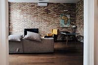 A living room with a sofa, a television, an armchair and a map on the brick wall. Original public domain image from <a href="https://commons.wikimedia.org/wiki/File:Budapest_Apartment_(Unsplash).jpg" target="_blank" rel="noopener noreferrer nofollow">Wikimedia Commons</a>
