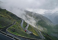 Cars driving down a windy road down a mountain covered in mist. Original public domain image from Wikimedia Commons
