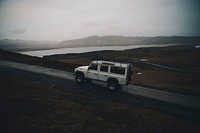 A white SUV driving up a dirt road in the mountains. Original public domain image from <a href="https://commons.wikimedia.org/wiki/File:The_Climb_to_Dyrh%C3%B3laey_(Unsplash).jpg" target="_blank" rel="noopener noreferrer nofollow">Wikimedia Commons</a>