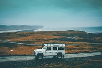 A white off-road vehicle on a dirt road with a misty shoreline at the back. Original public domain image from Wikimedia Commons