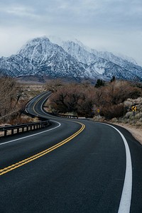 Road leading to mountains alongside with tree and grass fields. Original public domain image from Wikimedia Commons