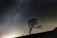 Silhouette of a man standing next to a tree under the starry night sky in Cromarty. Original public domain image from Wikimedia Commons
