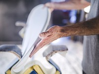 A blurry shot of a man's hands holding a handmade part of a surfboard. Original public domain image from Wikimedia Commons
