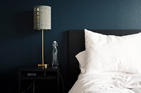 A white bed, silver lamp, empty carafe, blue wall, and a bedside table at Alta Yorktown Apartments. Original public domain image from Wikimedia Commons