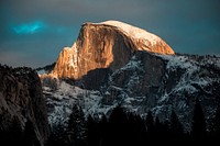 The sun lighting up a snowcapped Half Dome peak at California's Yosemite National Park. Original public domain image from Wikimedia Commons