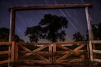 An archway with a gated fence in Lebanon, featuring blurry star trails in the background. Original public domain image from Wikimedia Commons