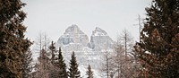 A wintry landscape with evergreen trees and two sharp mountain peaks near Lake Misurina. Original public domain image from Wikimedia Commons