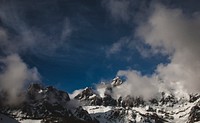Clouds shrouding a jagged snow-covered mountain ridge in Picos de Europa. Original public domain image from <a href="https://commons.wikimedia.org/wiki/File:Picos_de_Europa_mountains_in_clouds_(Unsplash).jpg" target="_blank" rel="noopener noreferrer nofollow">Wikimedia Commons</a>