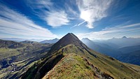 View from a grassy ridge on a green mountainous landscape near Monte Lodin. Original public domain image from Wikimedia Commons