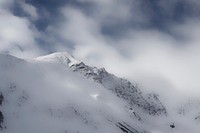 Clouds cover a snowy mountain ridge. Original public domain image from Wikimedia Commons