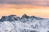 A snowy mountain ridge under an orange sky near Seiser Alm. Original public domain image from Wikimedia Commons