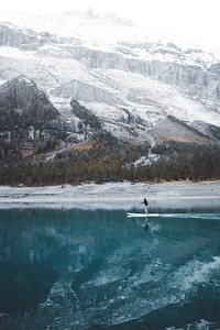 A man on a paddle board on an azure lake in the mountains. Original public domain image from Wikimedia Commons