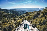 A mountaineer's outstretched legs on a rocky ridge. Original public domain image from Wikimedia Commons