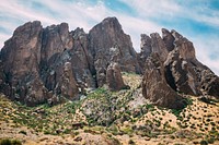 Rock formations stand tall among desert foliage on a hot day. Original public domain image from <a href="https://commons.wikimedia.org/wiki/File:Desert_Formations_(Unsplash).jpg" target="_blank" rel="noopener noreferrer nofollow">Wikimedia Commons</a>