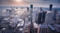 Drone view of a city with tall buildings and a cloud lined over it. Original public domain image from Wikimedia Commons