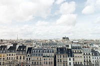 A skyline view of Paris buildings on a bright day with Eiffel Tower in the distance. Original public domain image from <a href="https://commons.wikimedia.org/wiki/File:Paris_buildings_with_clouds_(Unsplash).jpg" target="_blank" rel="noopener noreferrer nofollow">Wikimedia Commons</a>