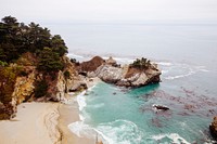 View of rock cliffs and a sand beach by the ocean at McWay Falls. Original public domain image from Wikimedia Commons