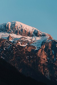 A steep craggy mountain face with its crest covered in snow in Berchtesgaden. Original public domain image from <a href="https://commons.wikimedia.org/wiki/File:Wild_Sunset_(Unsplash).jpg" target="_blank" rel="noopener noreferrer nofollow">Wikimedia Commons</a>