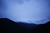 Cloudy blue sky shines on a silhouette of mountains in Falls Creek. Original public domain image from <a href="https://commons.wikimedia.org/wiki/File:Blue_dusk_in_the_mountains_(Unsplash).jpg" target="_blank" rel="noopener noreferrer nofollow">Wikimedia Commons</a>